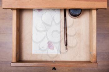 above view of nib pen, ink, vintage envelope in open drawer of nightstand