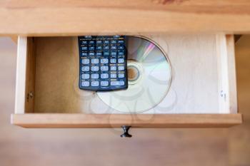 top view of scientific calculator and a CD with the experimental data in open drawer of nightstand