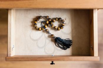 above view of rosary from tiger-eye gems in open drawer of nightstand