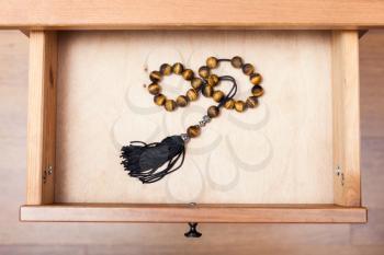 top view of rosary from tigers eye gemstone in open drawer of nightstand