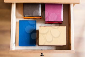top view of several little books in open drawer of nightstand