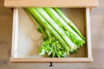 above view of green celery stalks in open drawer of nightstand
