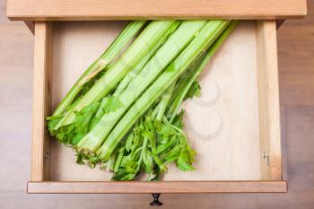 top view of celery stalks in open drawer of nightstand