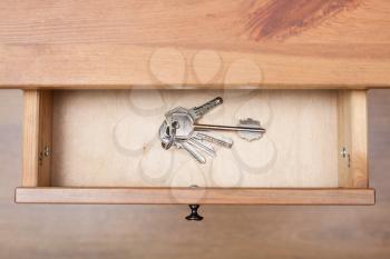 top view of bunch of door keys on ring in open drawer of nightstand
