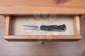 above view of foldable knife in open drawer of nightstand