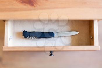 top view of pocket knife in open drawer of nightstand