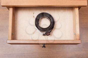 top view of leather belt in open drawer of nightstand