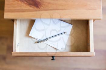 above view of folded sheet of paper and pen in open drawer of nightstand