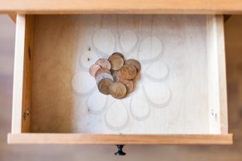 top view of pile of british coins in open drawer of nightstand
