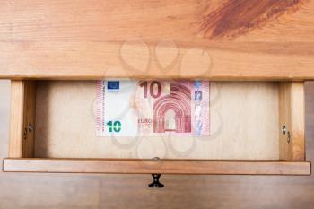 top view of one ten euro banknote in open drawer of nightstand