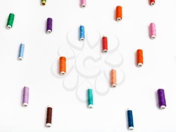 side view of many spools of sewing thread on white background
