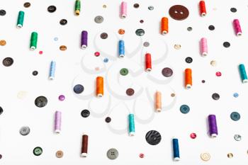 side view of spools of thread and various buttons on white background