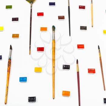 side view of paint brushes and watercolors arranged on white background