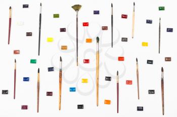 top view of paint brushes and watercolors arranged on white background