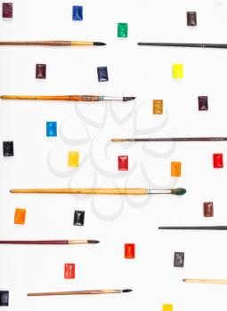 paint brushes and watercolors arranged on white background
