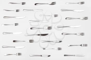 top view of table knives and forks arranged on white background