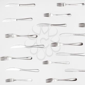 above view of many table knives and forks on white square background