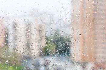 rainy weather in city - view of wet window glass of urban house