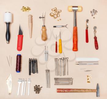 above view of collection various leathercrafting tools on natural leather surface