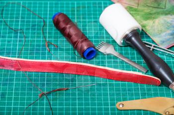 leather working - new belt, sewing tools and stitching chisel on self-healing mat