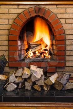 wood logs and fire in indoor brick fireplace in country cottage
