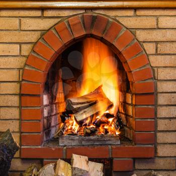 wood burning in indoor brick fireplace in country cottage