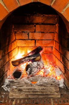ash, coal and burning wooden logs in fireplace in country cottage