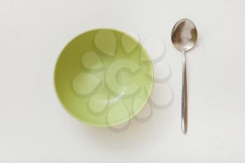 top view of green bowl and spoon on white plastering plate