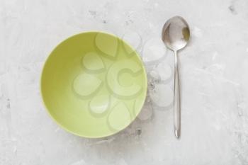 top view of green bowl and spoon on gray concrete plate