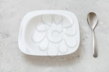 square white bowl and spoon on gray concrete board