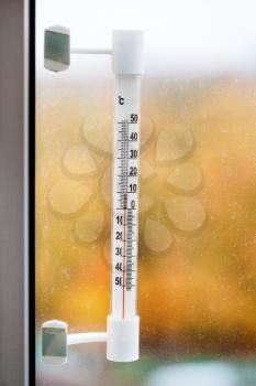 outdoor thermometer on home window pane in autumn day