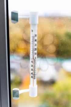 outdoor thermometer on home window glass in autumn day