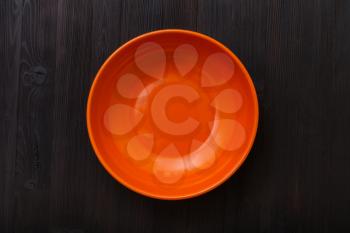 top view of one orange bowl on dark brown table