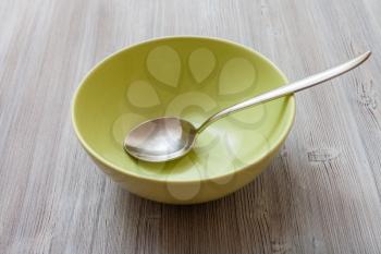 one green bowl with steel spoon on gray brown table