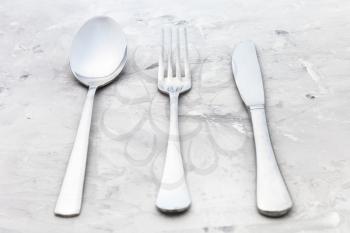 food concept - serving set from table knife, fork, soup spoon on concrete surface