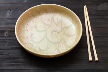 one yellow green plate and chopsticks on dark brown board