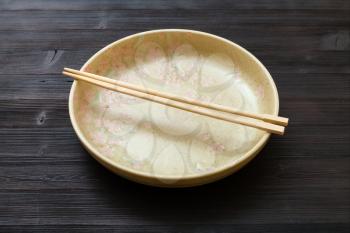 one yellow green plate with chopsticks on dark brown board