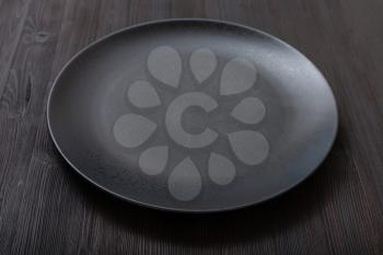one black plate on dark brown table