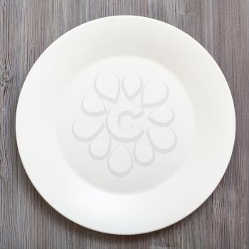 top view of one white plate on gray brown table