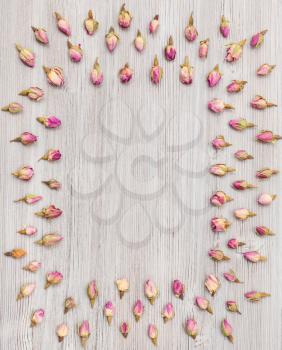 frame from many natural pink rose flower buds on wooden board