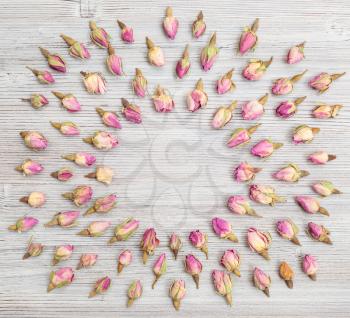 round frame from many natural pink rose flower buds on wooden board