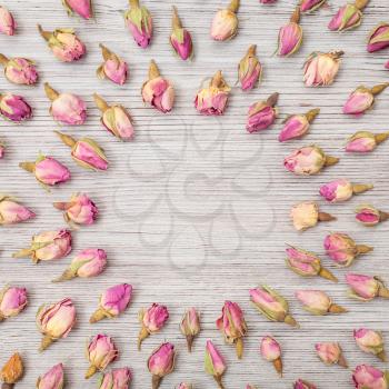 round frame from dried pink rose flower buds on wooden board