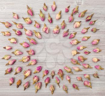 round frame from many natural pink rose flower buds on wooden plank