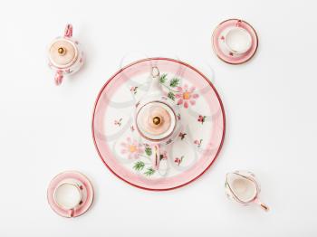 food concept - above view of pink porcelain tea set on white paper background