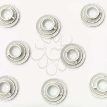 food concept - top view of several white cups and saucers on white background