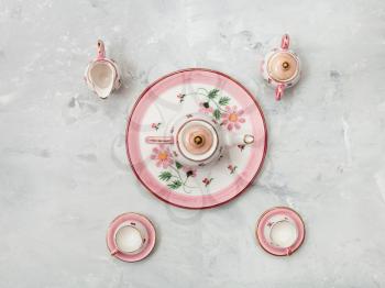 food concept - above view of pink porcelain tea set on gray concrete background