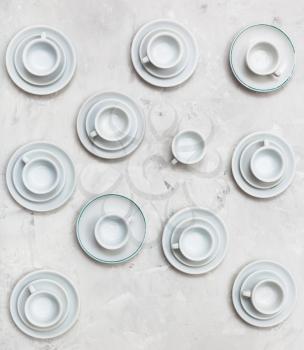 food concept - top view of many white cups and saucers on gray concrete background