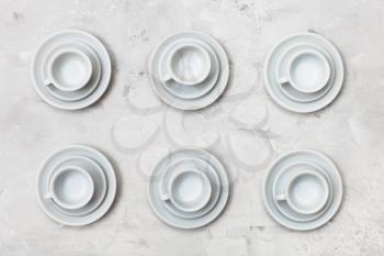 food concept - top view of six white cups and saucers on gray concrete background