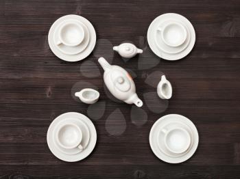 food concept - top view of cups with saucers and tea set on dark brown table