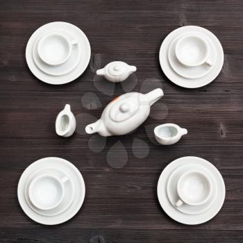food concept - above view of cups with saucers and tea set on dark brown board